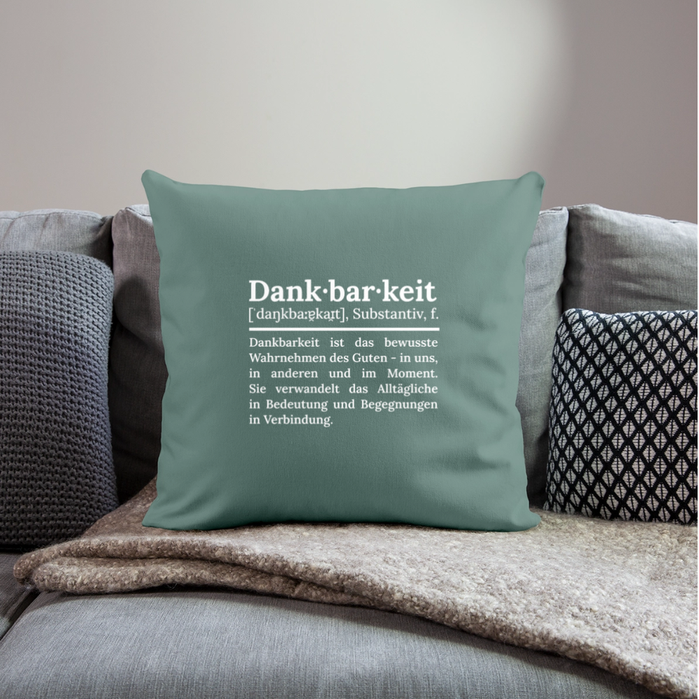 Design-Kissen „Dankfabrik“ in grün auf dem Sofa, hochwertiges Dekokissen mit Botschaft von Dankfabrik.