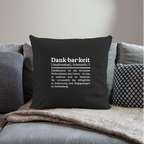 Design-Kissen „Dankfabrik“ in schwarz auf dem Sofa, hochwertiges Dekokissen mit Botschaft von Dankfabrik.