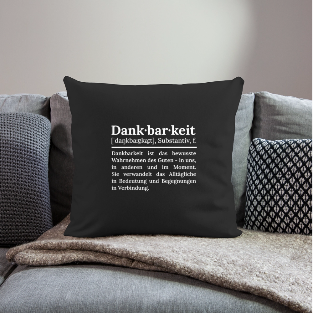 Design-Kissen „Dankfabrik“ in schwarz auf dem Sofa, hochwertiges Dekokissen mit Botschaft von Dankfabrik.